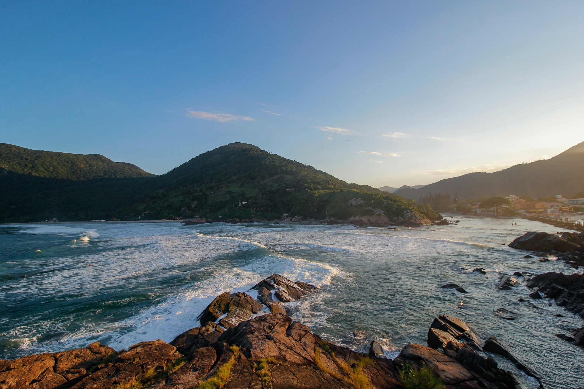 Sunset over the rocky coastline of Florianópolis with waves rolling into the bay